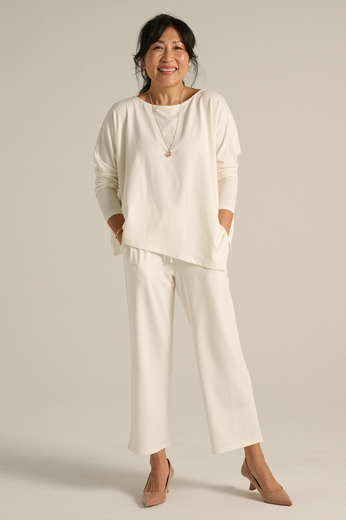 A model wearing a matching set of soft white trousers and a top, with side pockets and a drawstring waist.