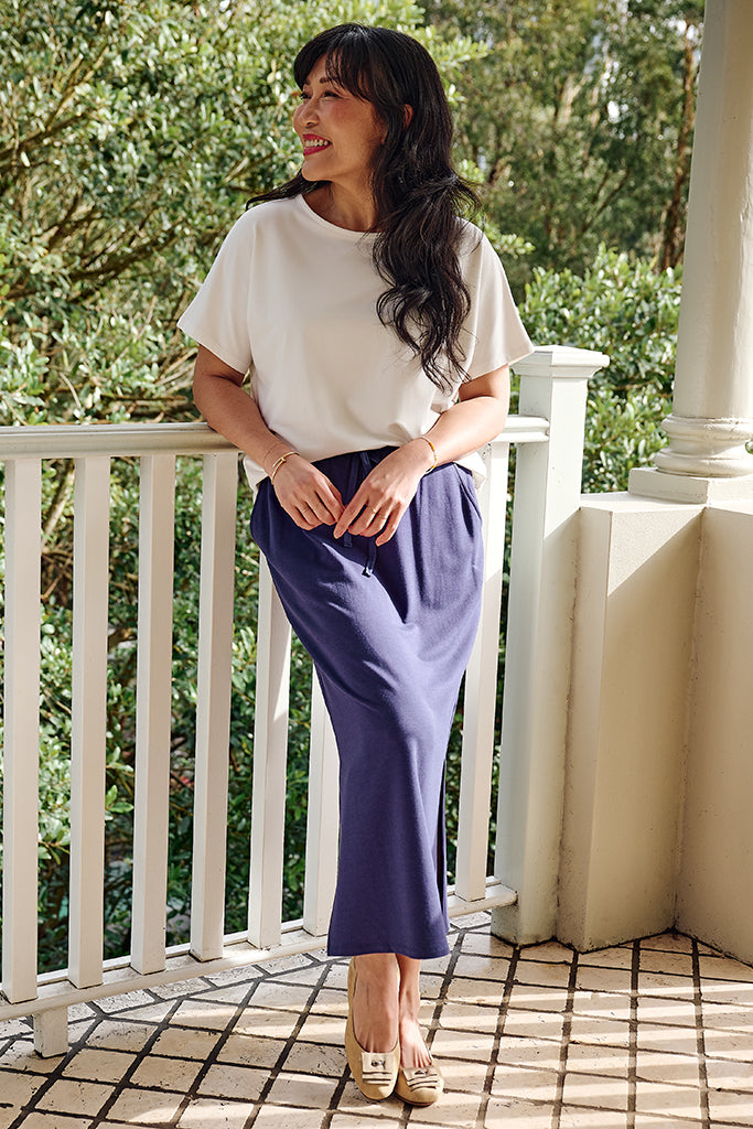Model wearing an effortless summer outfit, featuring a white bamboo tee and indigo midi skirt.