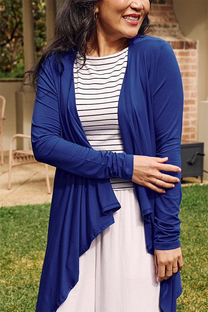 Close up of model wearing a lightweight cobalt cardigan paired with a striped singlet and white pants