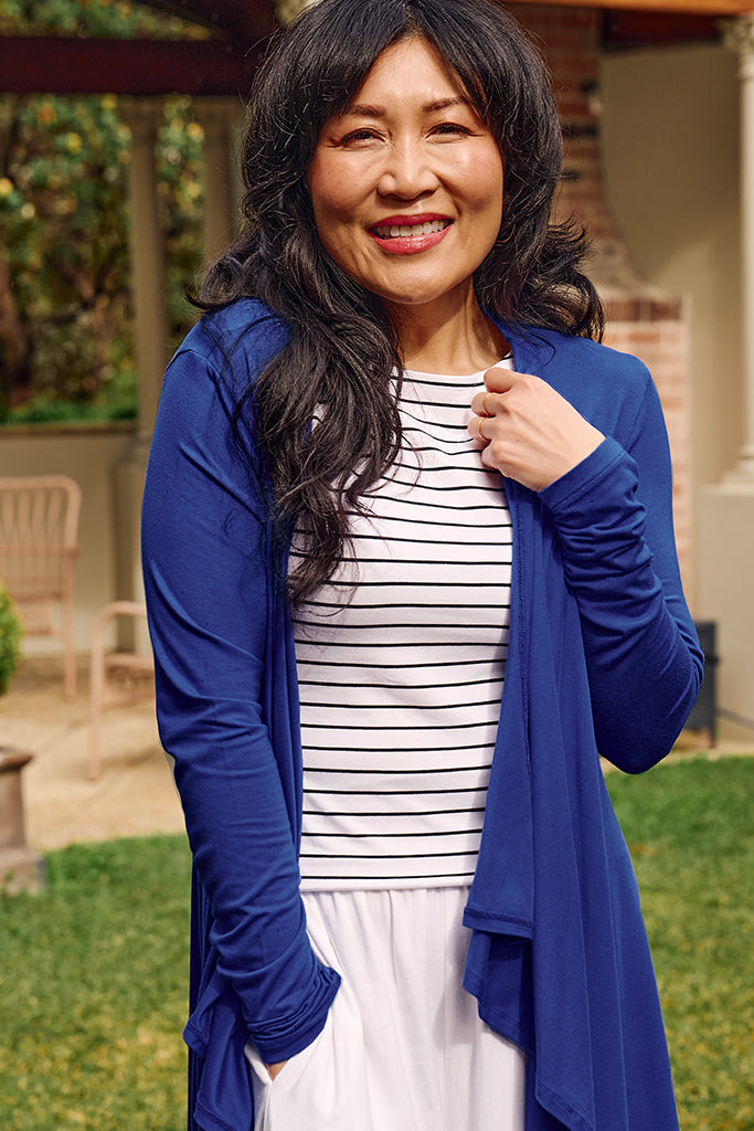 Close up of model wearing a cobalt bamboo cardigan and a striped high neck top outside