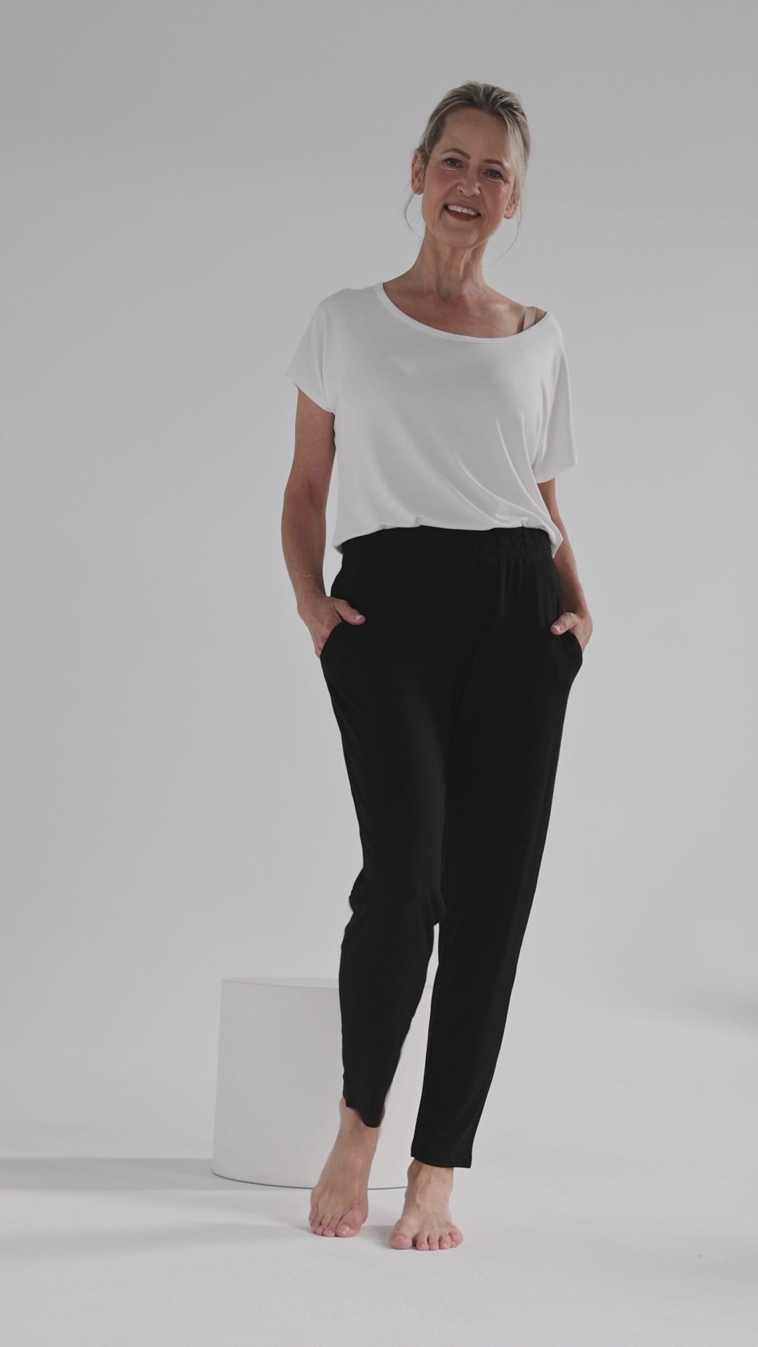 a woman wearing the Peggy pants in black with side pockets, tapered leg and an elasticated waistband