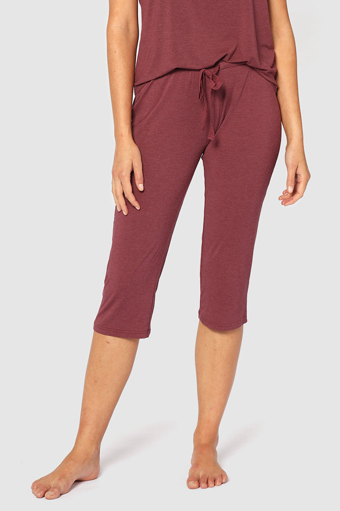 A model wearing burgundy 3/4 length pants with an elasticated drawstring waist.