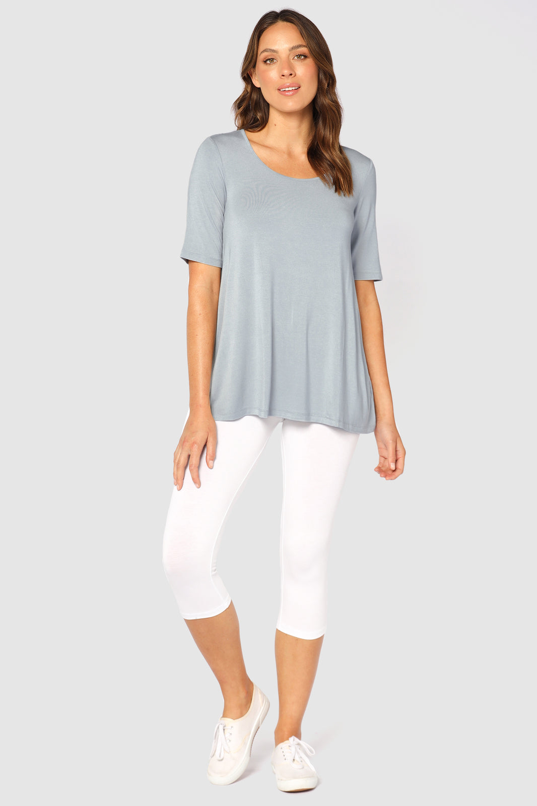 A tall woman wearing white 3/4 length leggings with a soft fabric waistband, paired with a black top.