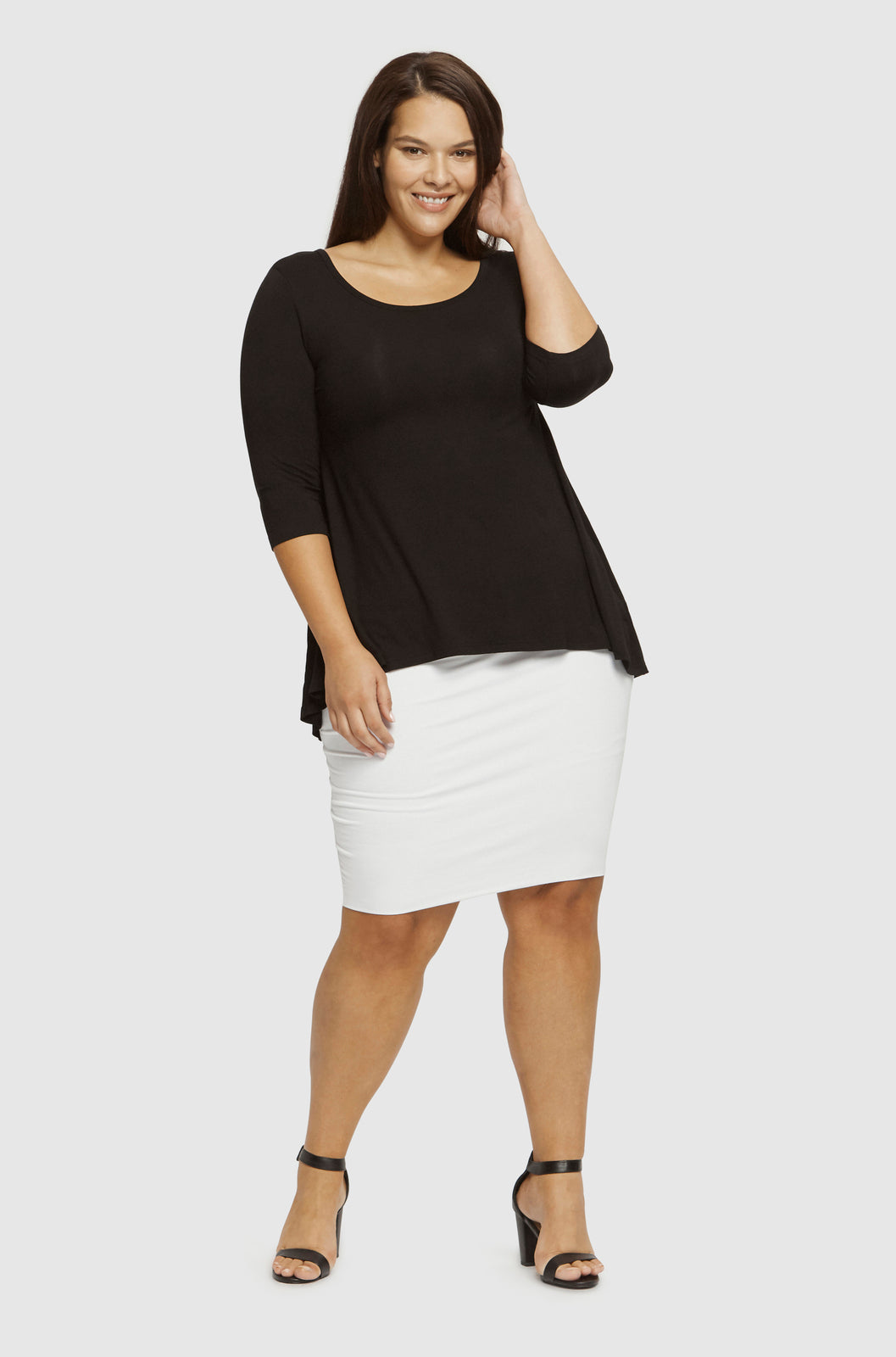 Curvy model wearing a relaxed black bamboo tee featuring 3/4 sleeves, scoop neckline and a longer length.
