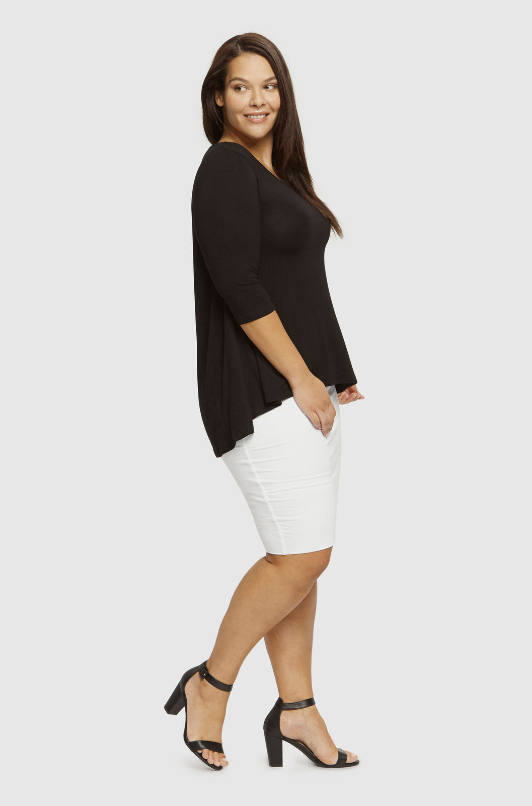 Side view of curvy model wearing a loose hi lo top made out of comfortable bamboo fabric.