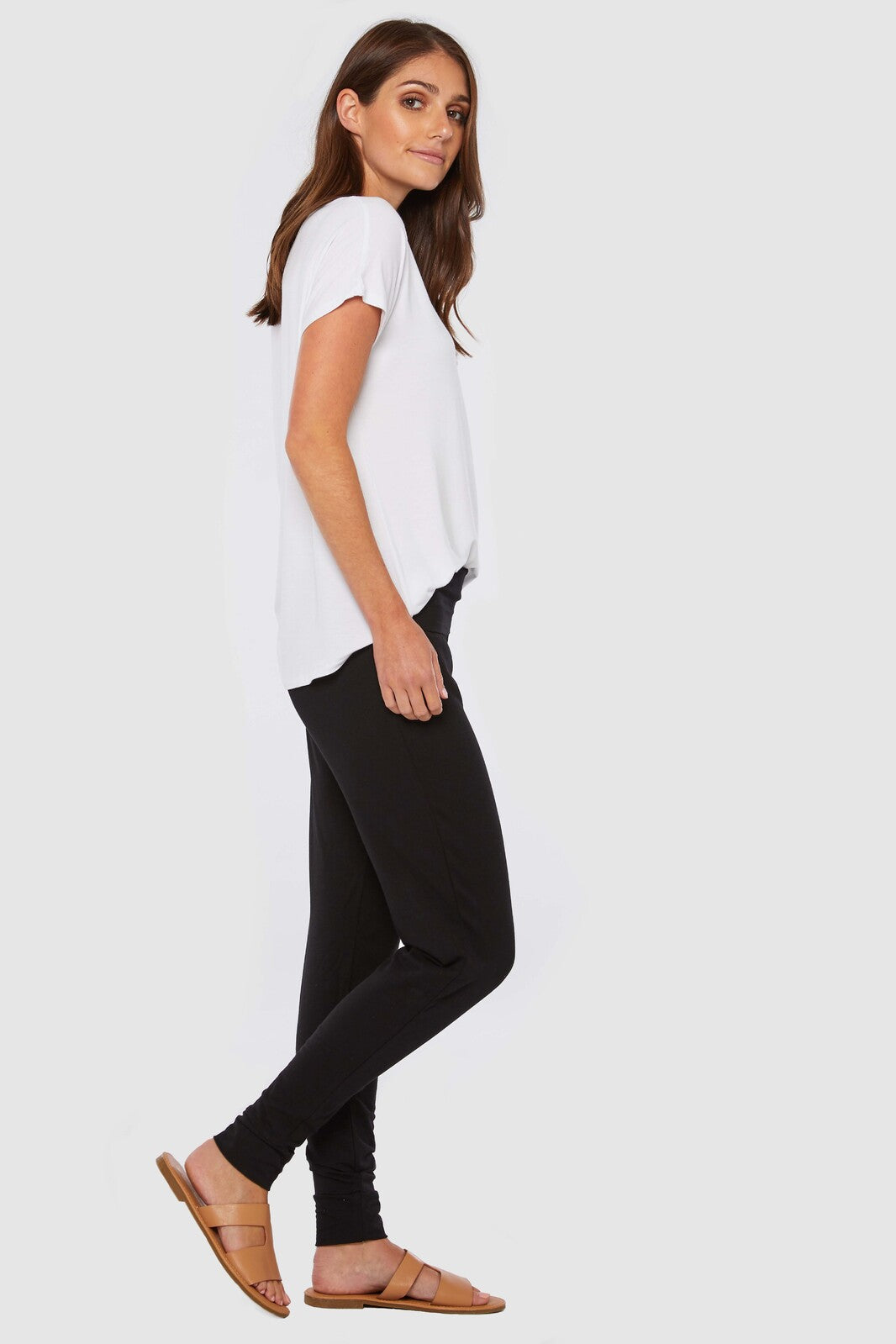 a side view of a woman wearing black cuffed slouch pants with wide stretchy and foldable waistband