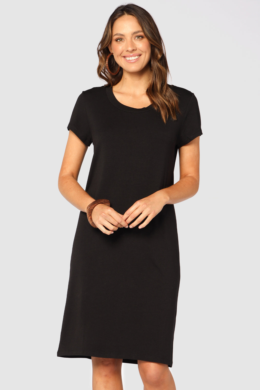A woman wearing a knee-length black t-shirt dress with short sleeves, round neckline, and a removable belt.