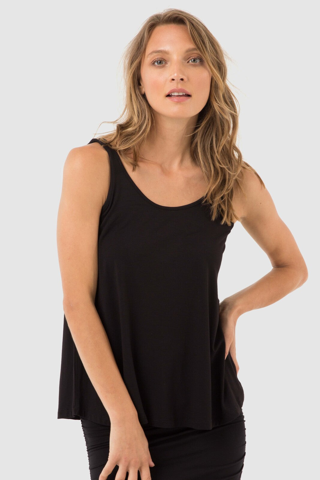 Standing women leaning slightly forward wearing black singlet with wide shoulder straps.