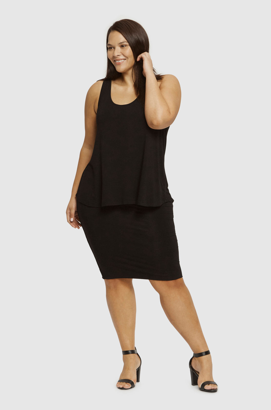 Curvy model wearing floaty black singlet with black skirt in black sandals