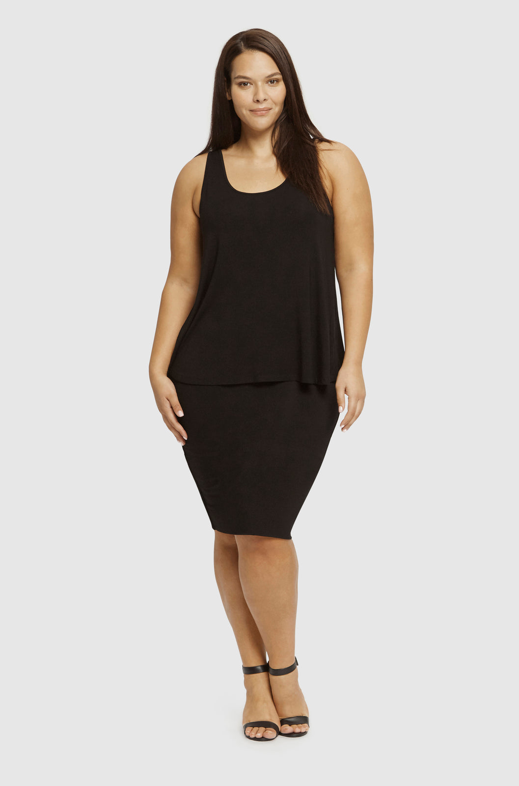 Front view of a plus size model wearing a black relaxed singlet with a fitted black tube skirt.