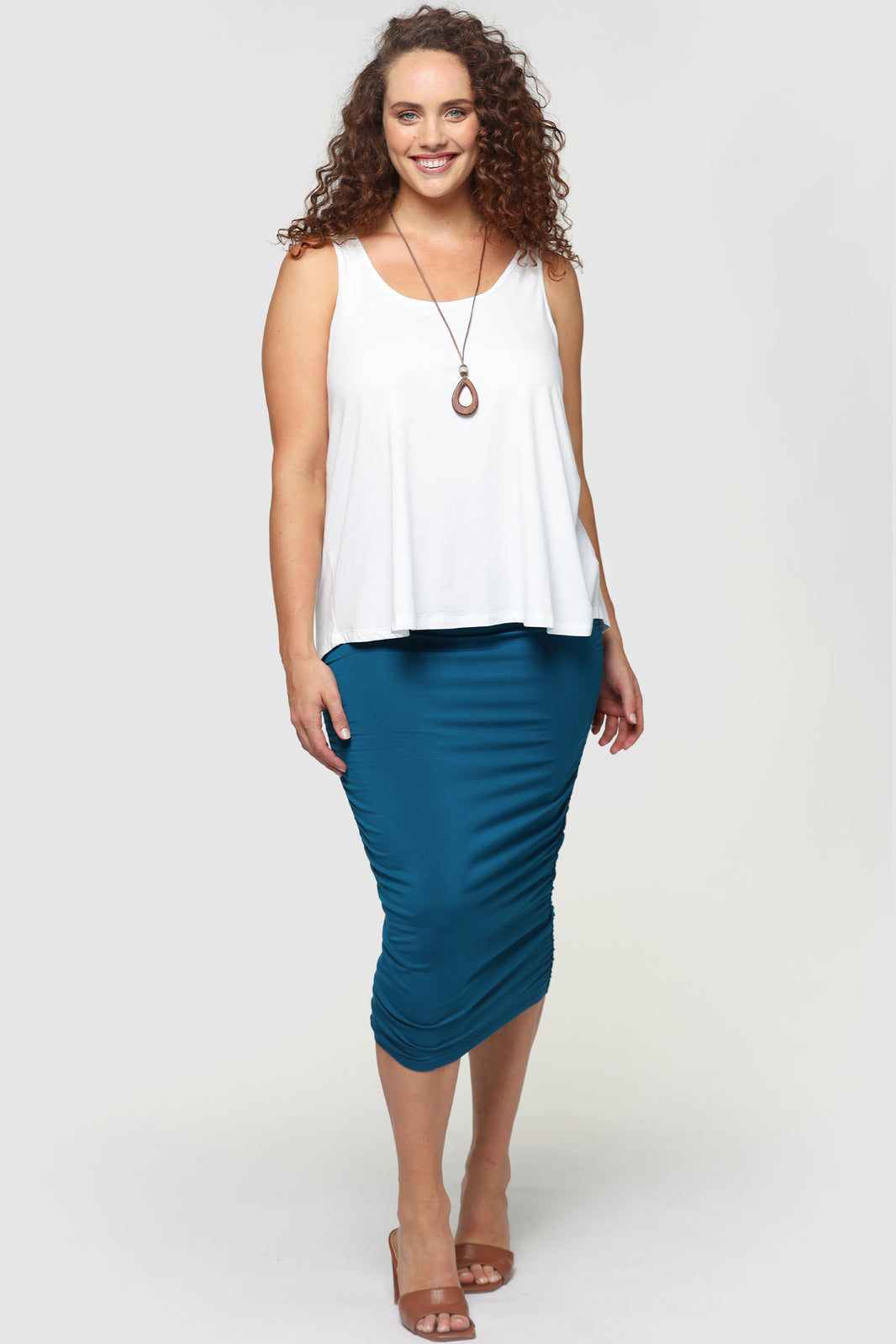 Model standing wearing a white a-line singlet and blue skirt.