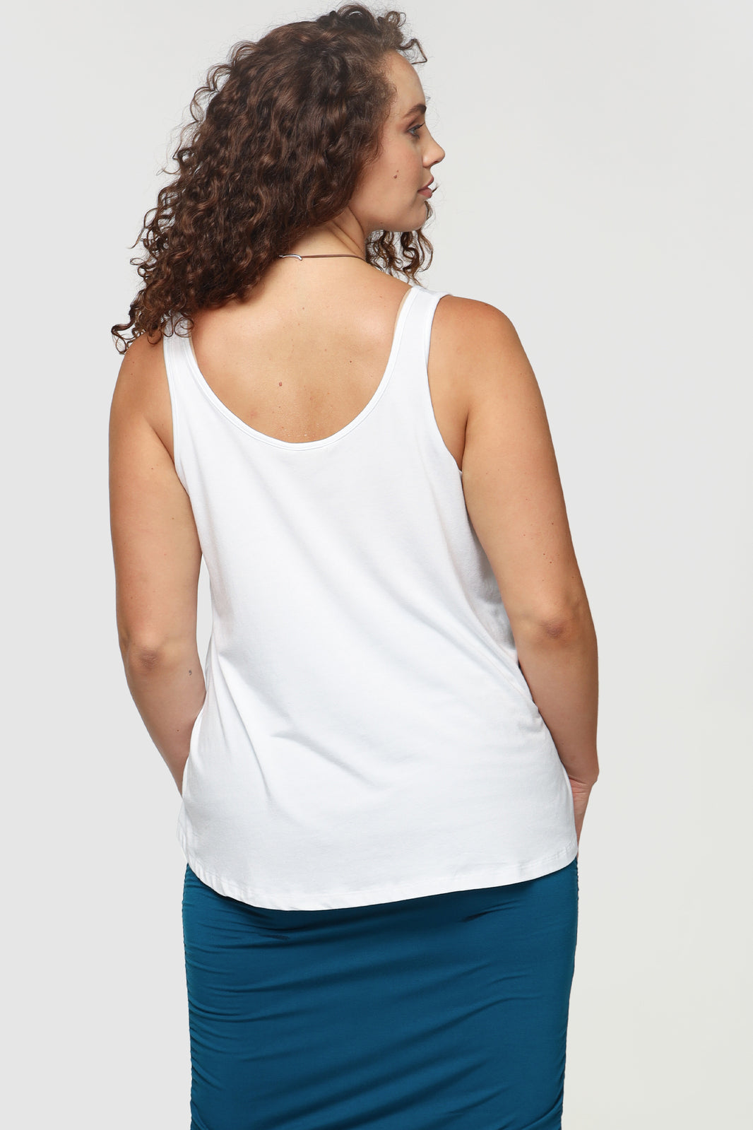 Back of plus size model wearing a white singlet with a curved neckline