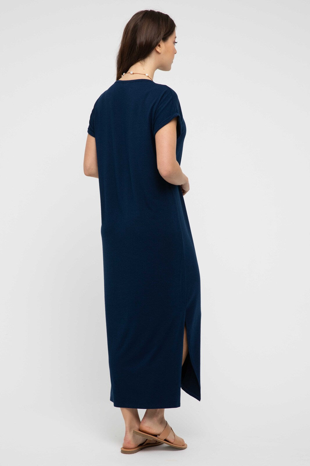 Back view of model in navy maxi dress with short sleeves, maxi length, and side split details