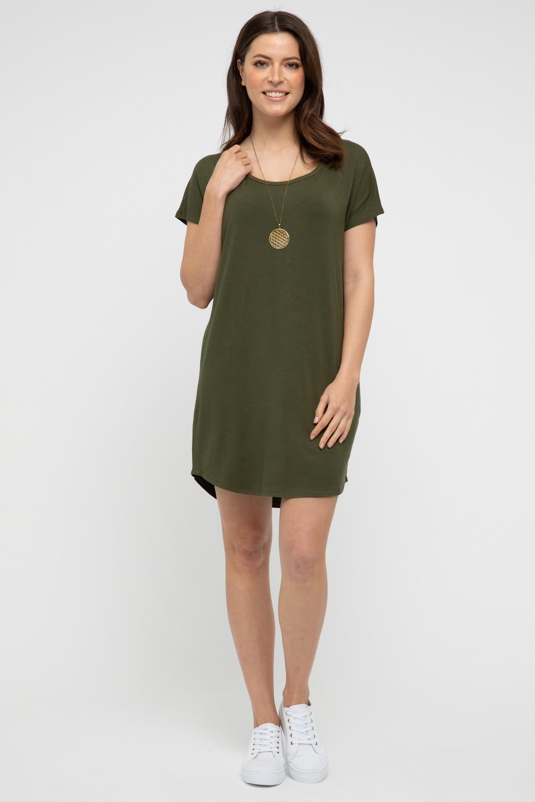 Model wearing an above knee length dress in dark olive, paired with white sneakers.