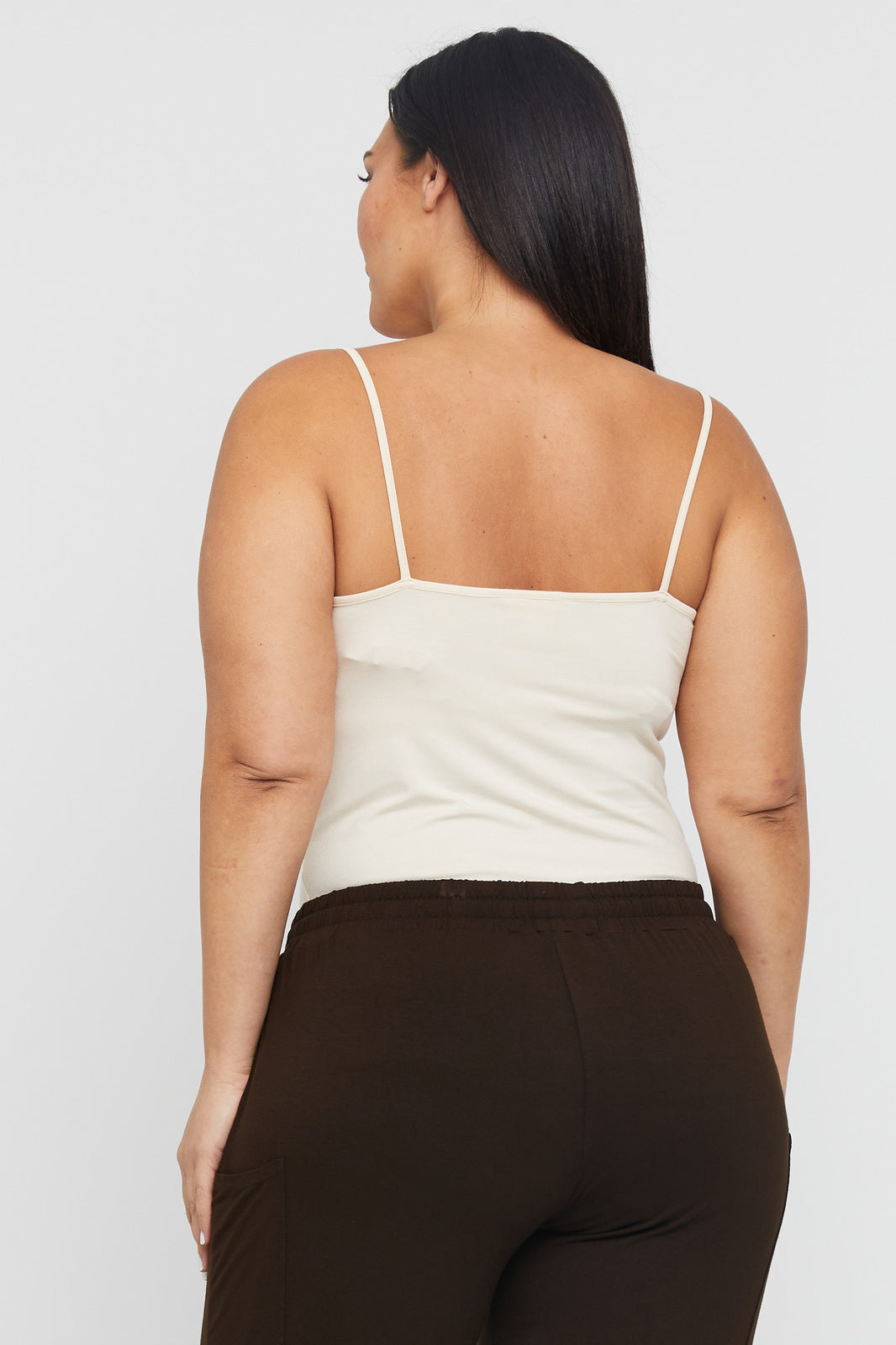 Showing the back of a plus size model wearing ecru coloured camisole with spaghetti straps.