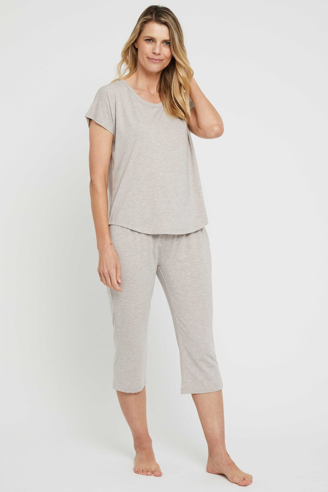 Woman wearing a relaxed pair of beige 3/4 pyjama pants with matching top.