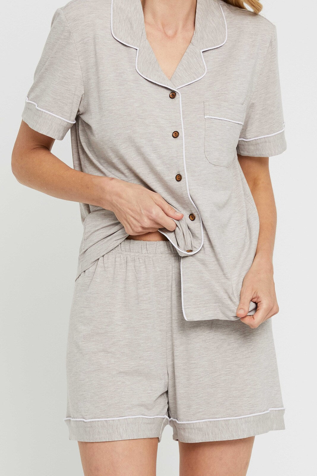 Close up of ladies PJ set in beige, featuring a collared shirt with buttons and shorts with an elasticated waistband.