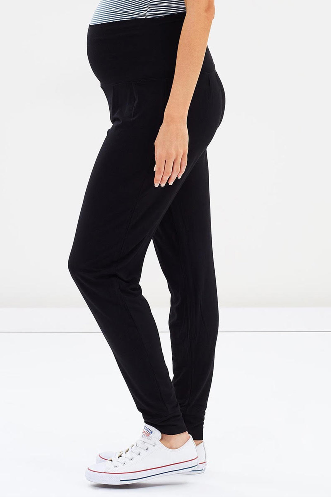 a side view of a pregnant woman wearing bamboo slouch pants with a wide fabric waistband