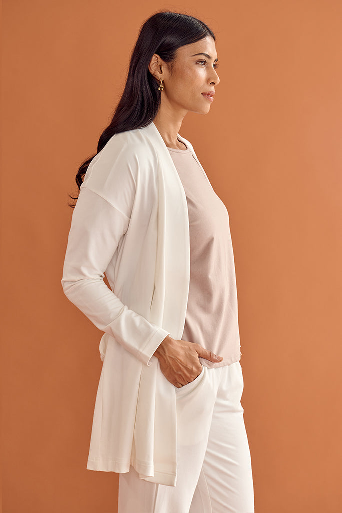 Side view of model wearing a relaxed white cardigan and matching pants.